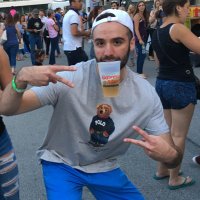 Man with hands in peace signs and cup in mouth at finish line of race